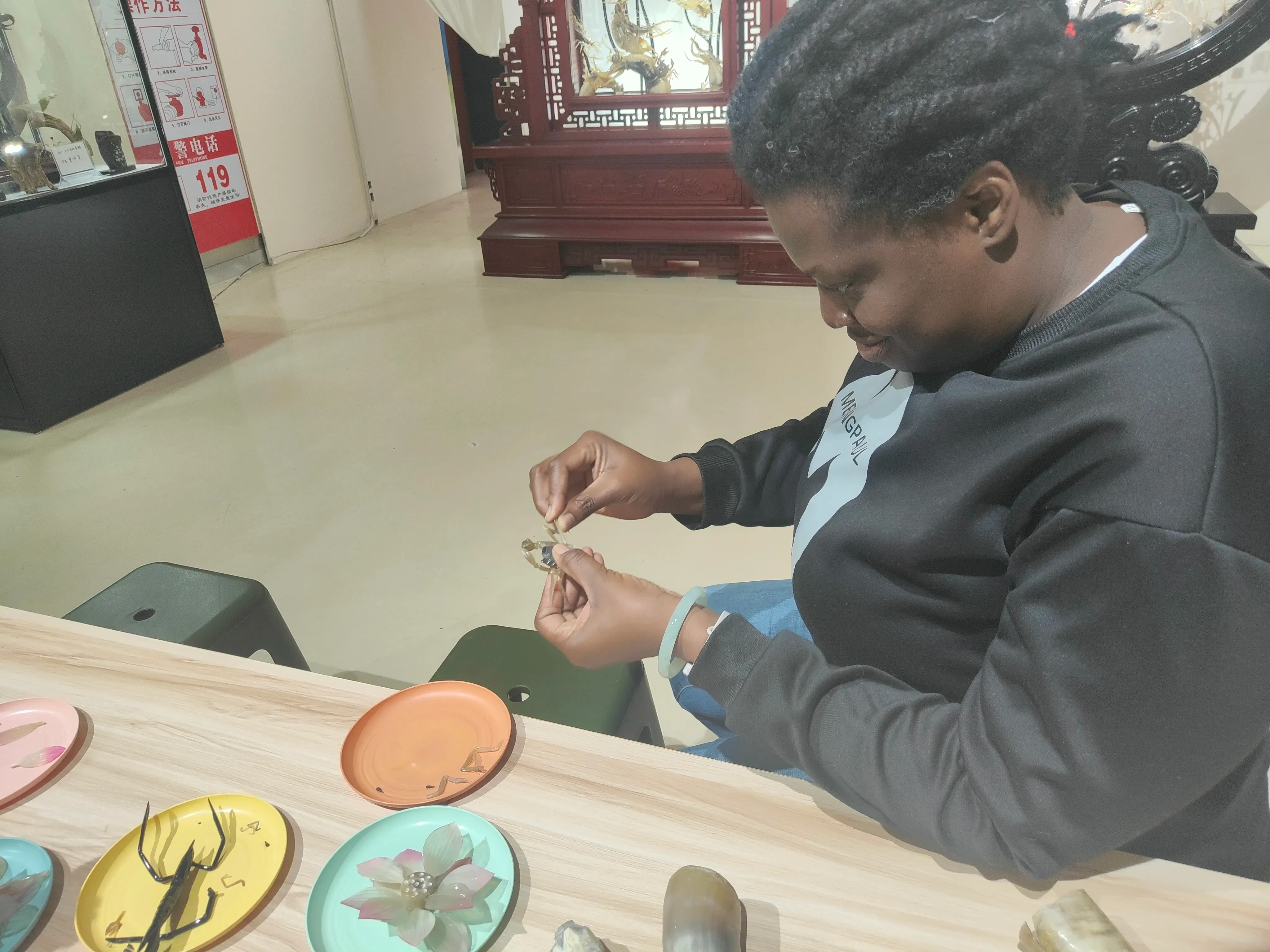Sandy getting hands-on experience with Ox Bone Carving at the Intangible Cultural Heritage Museum, learning the intricate art of piecing together lifelike animal figures